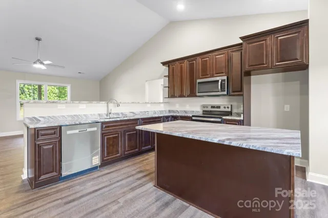 a kitchen with stainless steel appliances granite countertop a stove a sink and a microwave