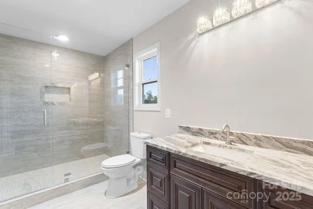 a bathroom with a granite countertop sink a toilet and shower