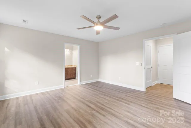an empty room with wooden floor and ceiling fan