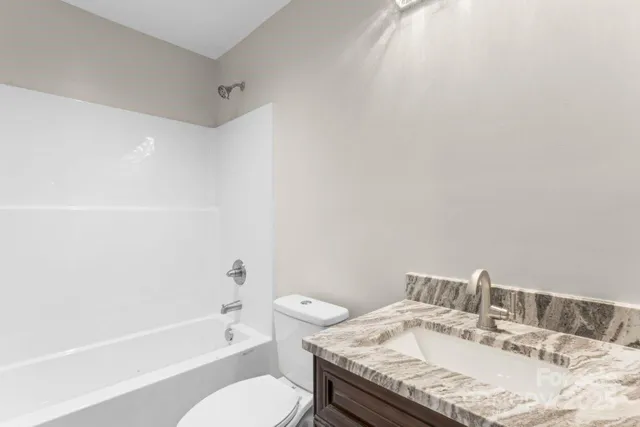 a bathroom with a granite countertop sink a toilet and bathtub