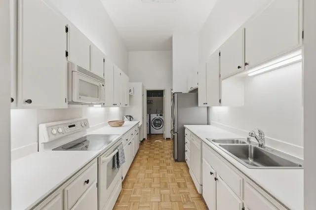 a kitchen with white cabinets and white appliances