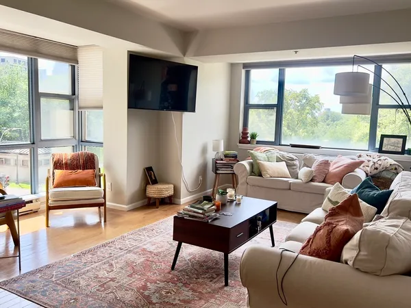 a living room with furniture a flat screen tv and a large window