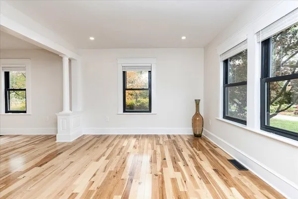 a view of empty room with wooden floor and fan