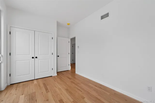 a view of an empty room with closet and wooden floor