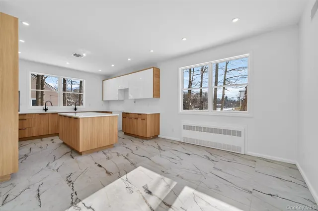 a large white kitchen with kitchen island a stove a sink a counter space and cabinets