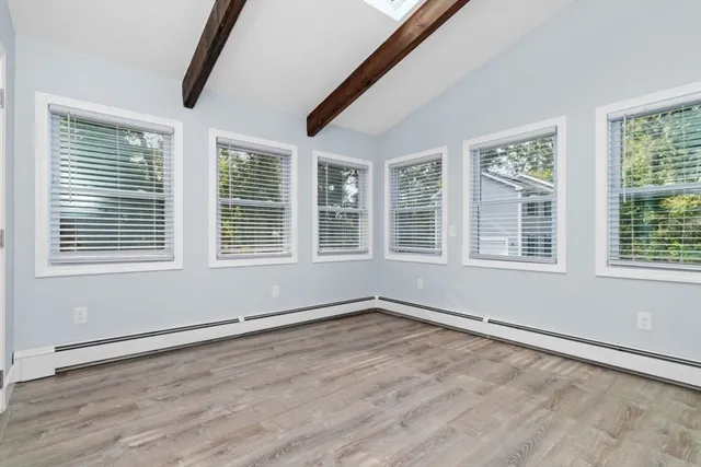 a view of an empty room with wooden floor and windows