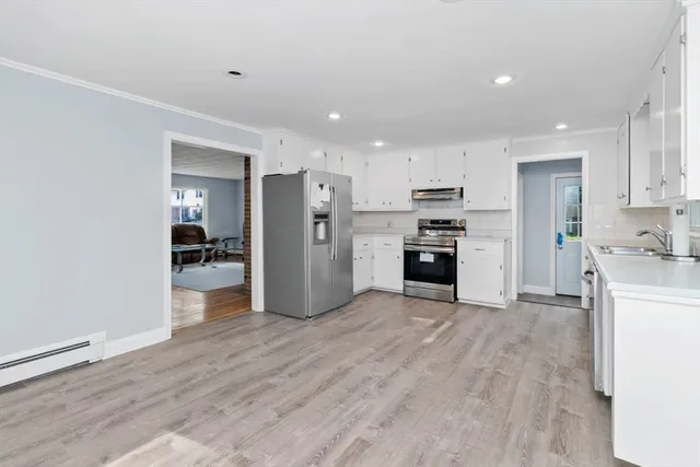 a view of a kitchen with refrigerator and wooden floor
