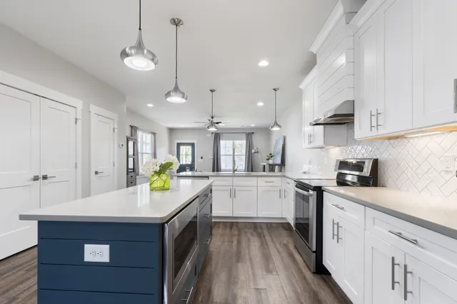 a kitchen with a sink dishwasher a stove and white cabinets with wooden floor