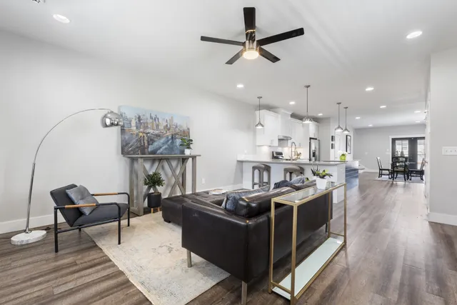 a living room with stainless steel appliances kitchen island a table and chairs in it