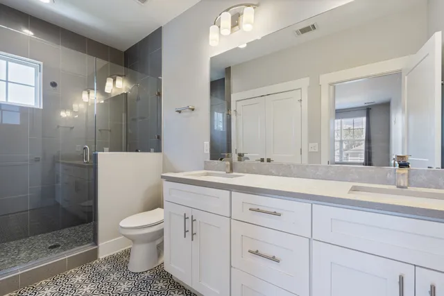 a bathroom with a toilet a sink a glass door a shower a mirror and vanity