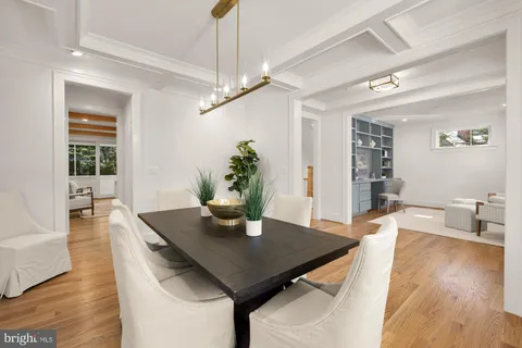 a large white kitchen with kitchen island a stove a sink dishwasher and white cabinets with wooden floor