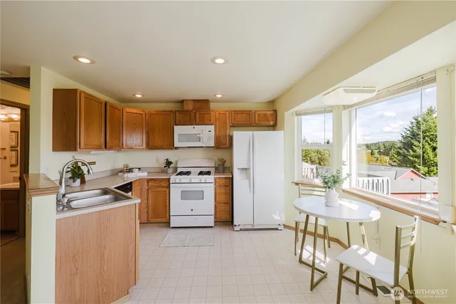 a kitchen with stainless steel appliances kitchen island granite countertop a stove a refrigerator a oven a sink with island and chairs in it