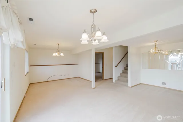 an empty room with chandelier fan and windows
