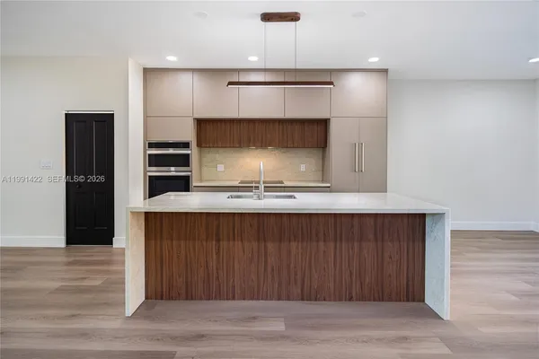 a kitchen with kitchen island a counter top space a sink a stove and a refrigerator