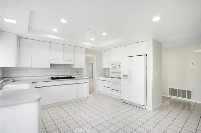a kitchen with a stove a refrigerator and white cabinets