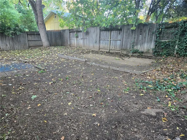 a backyard of a house with large trees and wooden fence