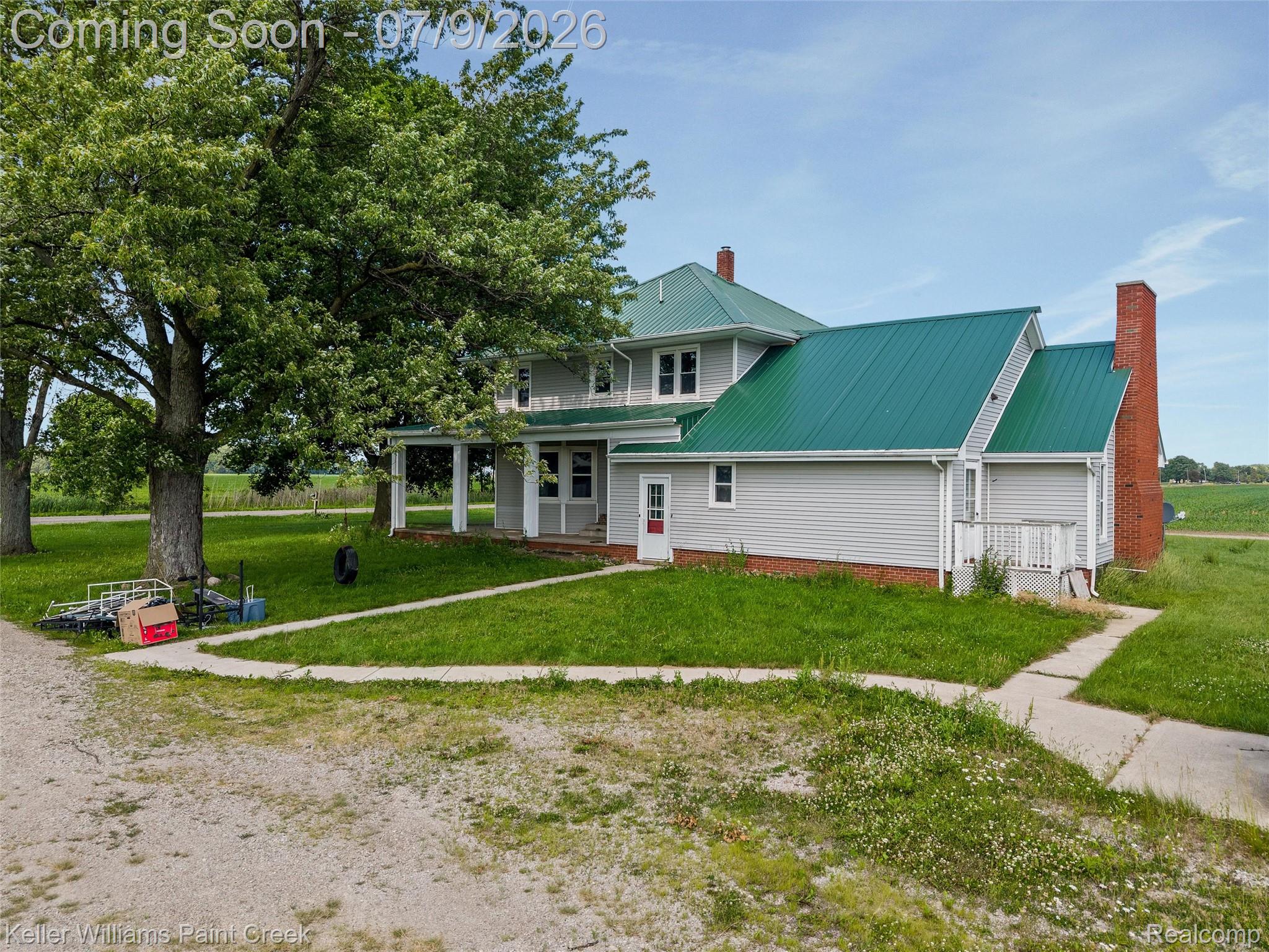 28780 School Section Road Richmond, MI 48062 - Photo 48 of 50 Property exterior featuring light gray siding, a vibrant green metal roof, and a red brick chimney