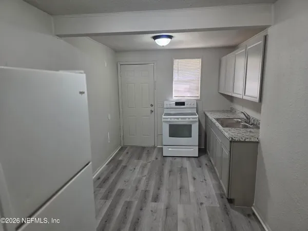 a kitchen with granite countertop a sink cabinets and stainless steel appliances