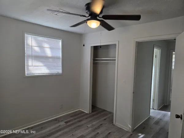 an empty room with closet and a chandelier fan