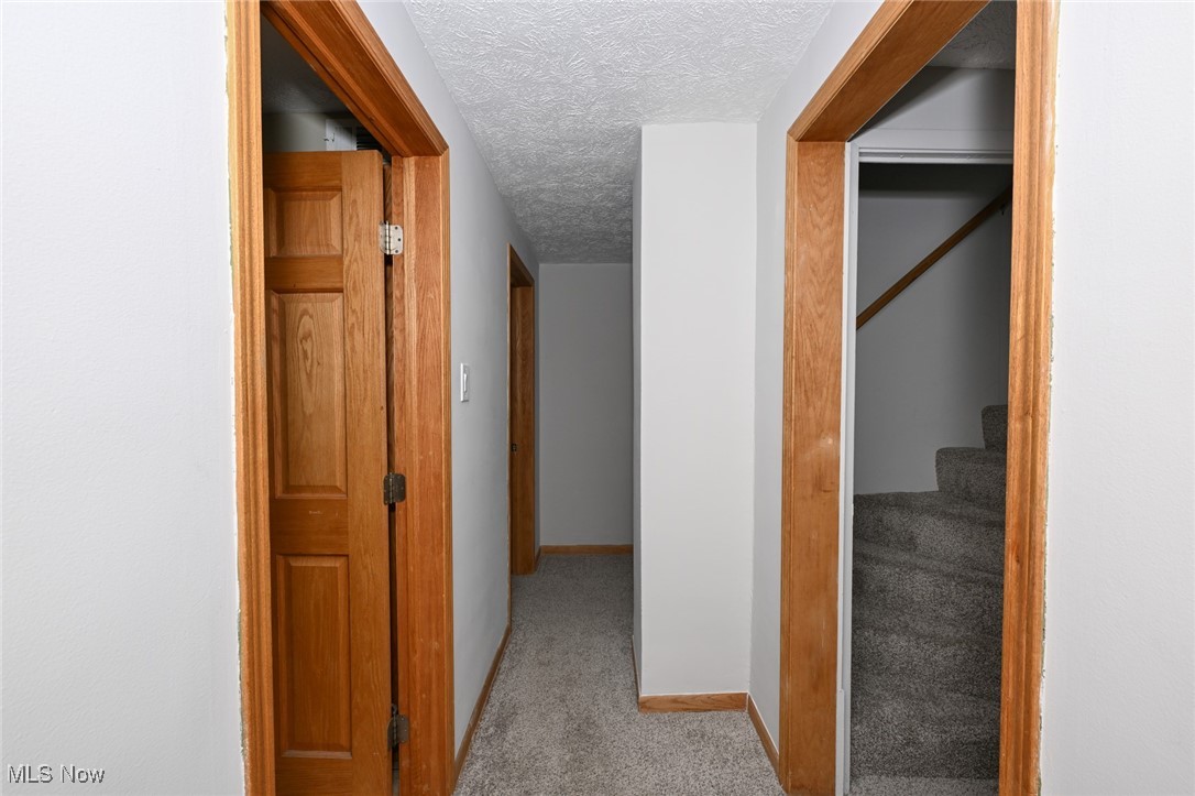 1164 Copley Road Akron, OH 44320 - Photo 27 of 50 Corridor featuring light carpet, a textured ceiling, baseboards, and stairs