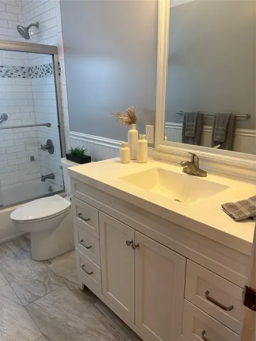 a bathroom with a granite countertop bathtub sink vanity mirror and toilet