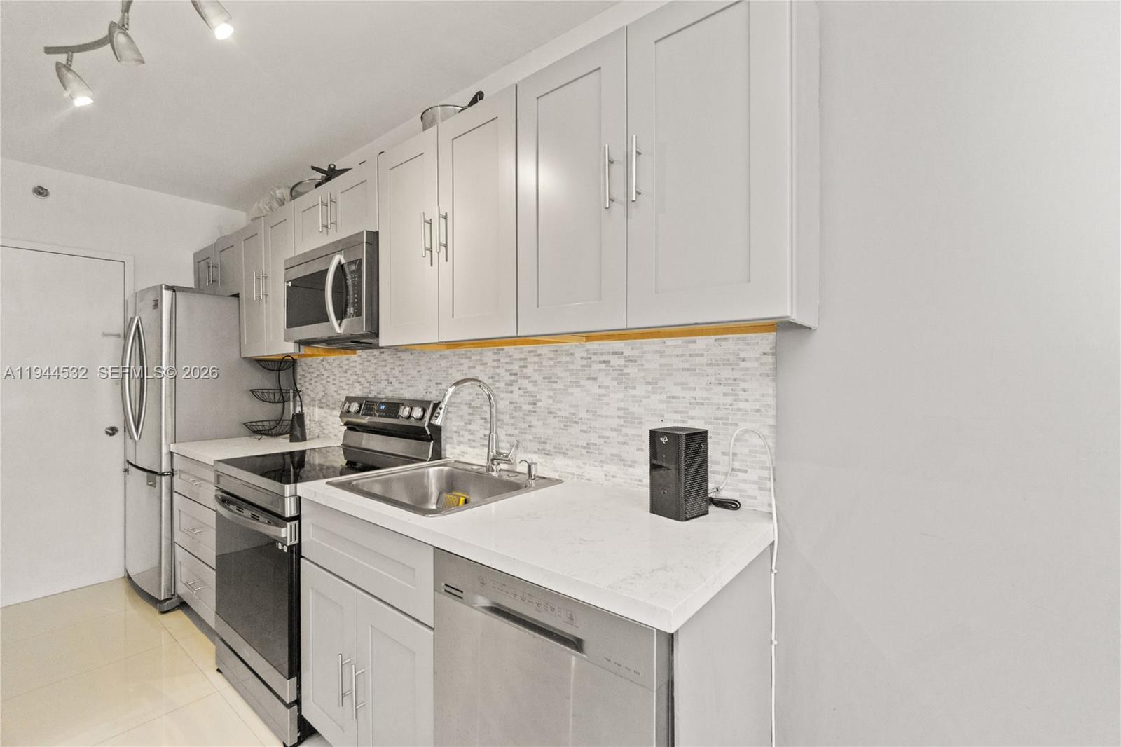 100 Lincoln Road, Unit 501 Miami Beach, FL 33139 - Photo 4 of 36 a kitchen with stainless steel appliances a sink a stove a microwave and cabinets