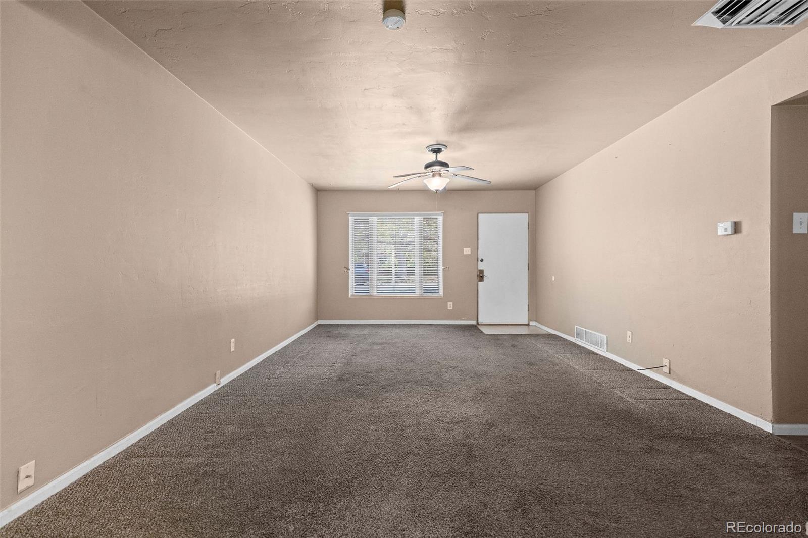 1283 Racine Street Aurora, CO 80011 - Photo 5 of 25 an empty room with windows and chandelier fan
