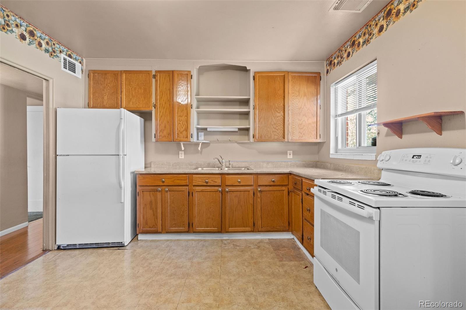 1283 Racine Street Aurora, CO 80011 - Photo 7 of 25 a kitchen with granite countertop a refrigerator a stove a sink and a granite counter tops with white cabinets