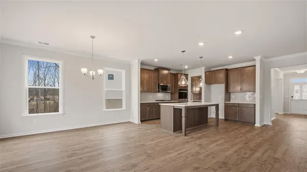 a large white kitchen with a refrigerator a sink dishwasher a stove and a dining table with wooden floor