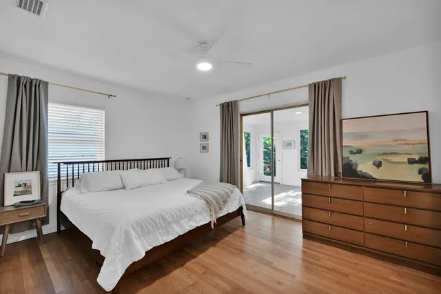 a large bedroom with a bed and large window with wooden floor
