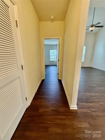 an empty room with wooden floor chandelier fan and windows
