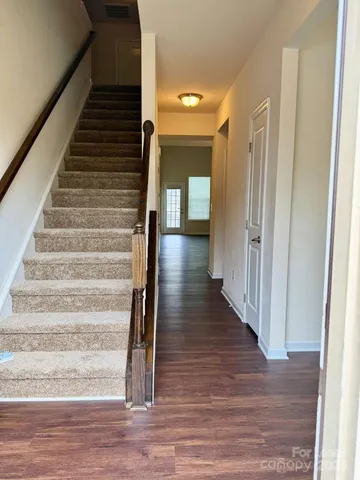 a view of a hallway with wooden floor and staircase