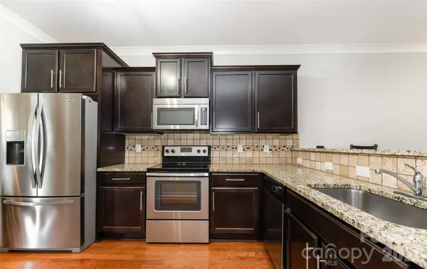 a kitchen with granite countertop a refrigerator stove and sink