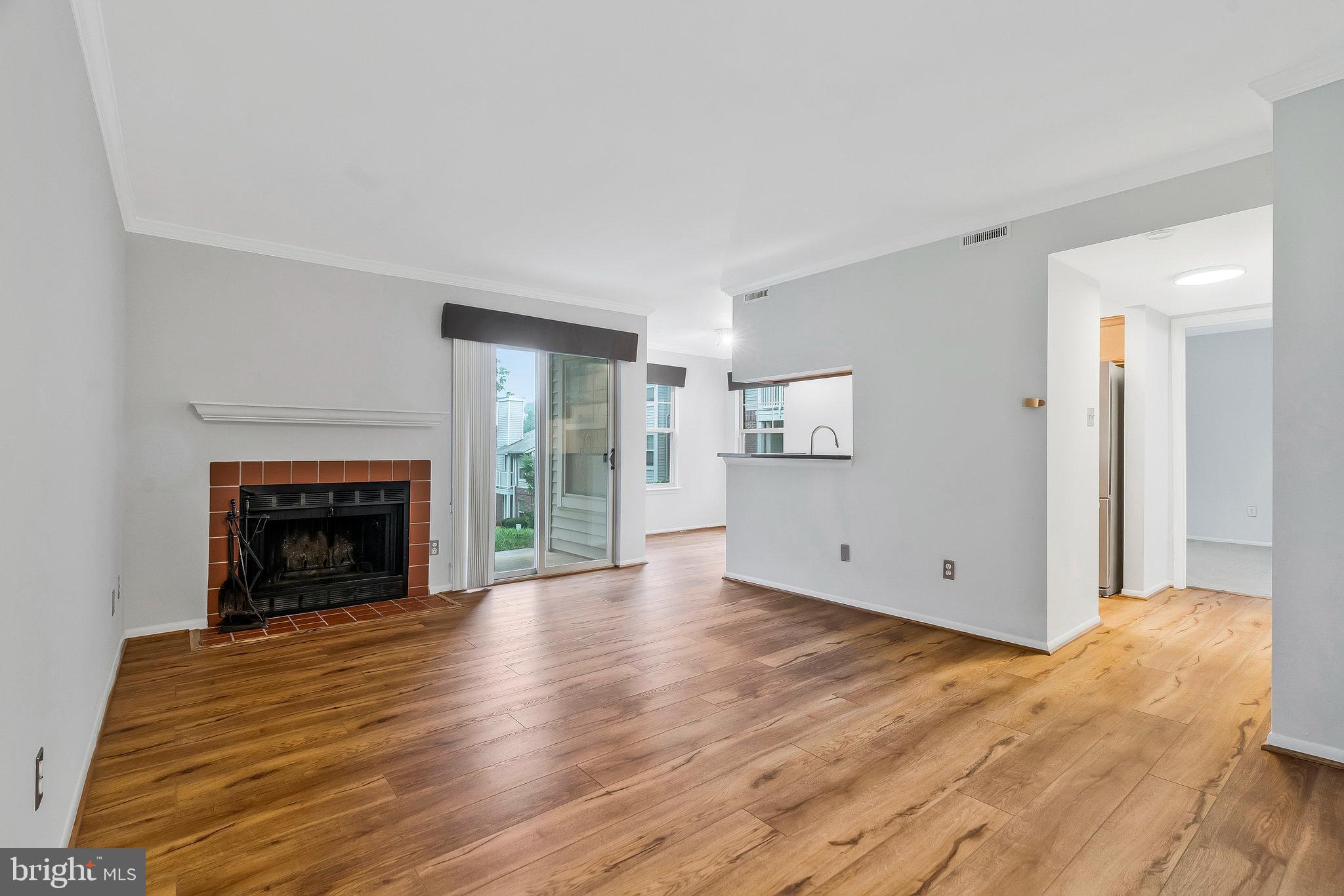 1701 Ascot Way, Unit 1701A Reston, VA 20190 - Photo 10 of 32 a view of an empty room with wooden floor fireplace and a window