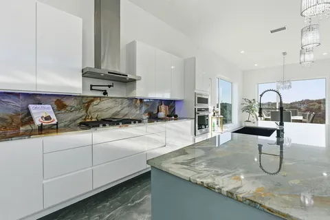a kitchen with granite countertop a sink a stove and cabinets
