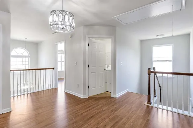 an empty room with wooden floor chandelier and windows