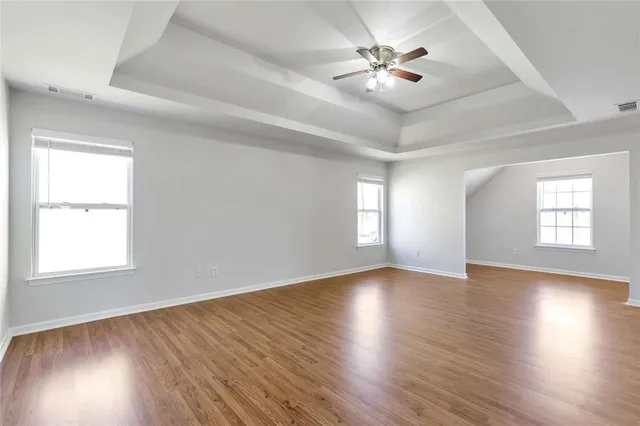 an empty room with wooden floor and windows