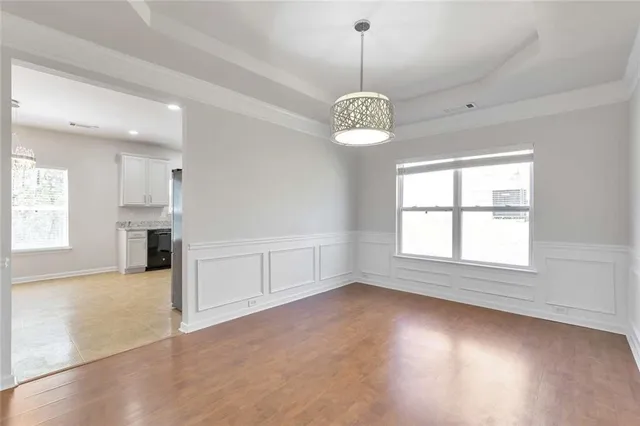 an empty room with chandelier outdoor seating and kitchen view