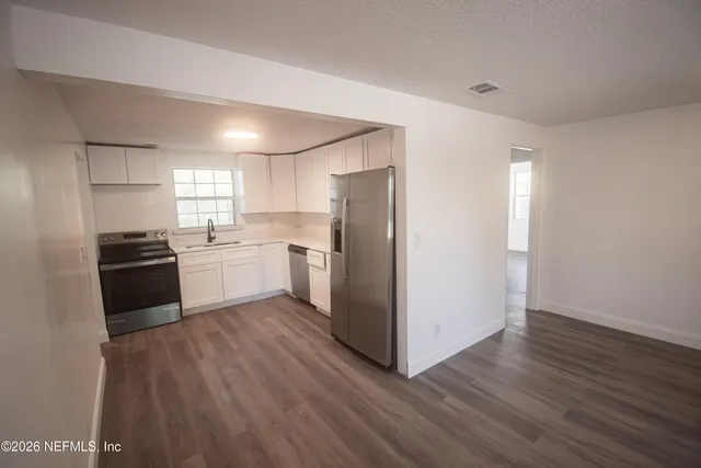 an empty room with wooden floor and windows