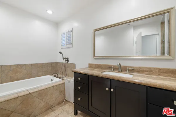 a bathroom with a tub a double vanity sink and mirror