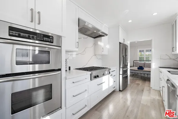 a kitchen with granite countertop cabinets stainless steel appliances and wooden floor