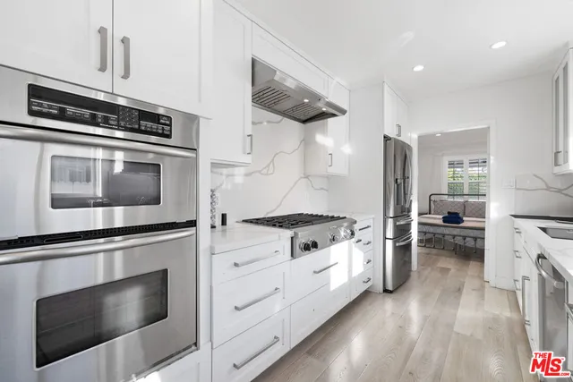 a kitchen with granite countertop cabinets stainless steel appliances and wooden floor