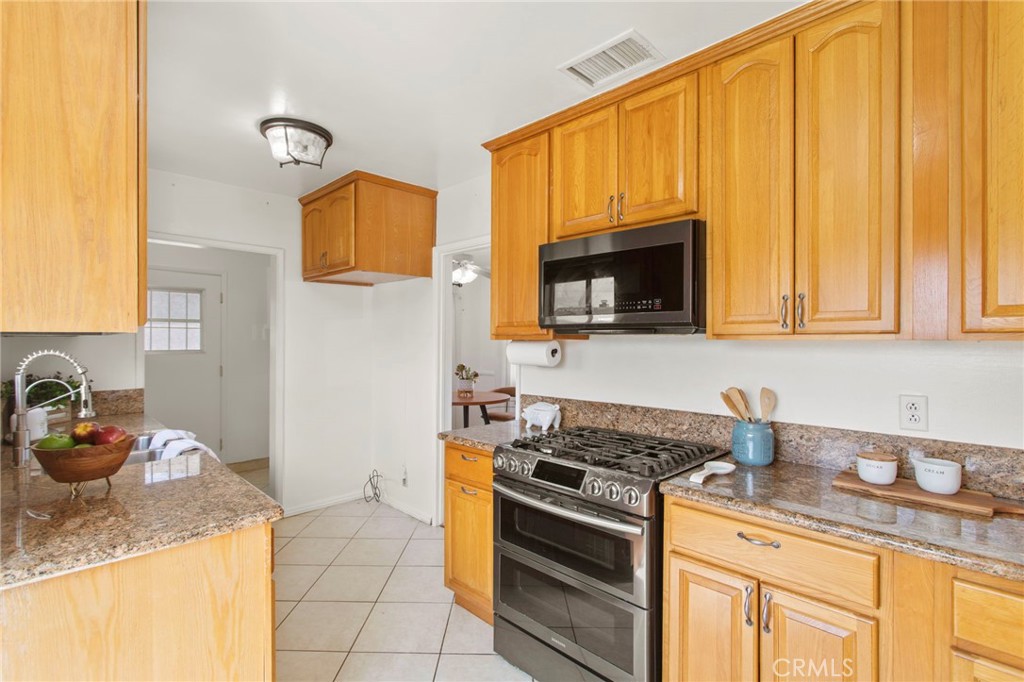 11339 Cecilia Street Downey, CA 90241 - Photo 7 of 17 a kitchen with stainless steel appliances granite countertop a sink stove and cabinets