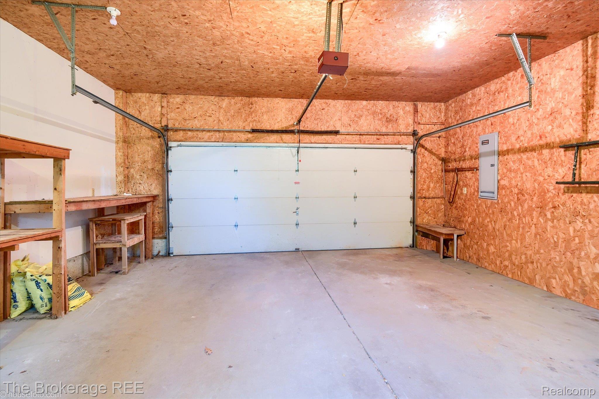 1077 Hadley Road Lapeer, MI 48446 - Photo 46 of 61 Spacious garage featuring a concrete floor, exposed OSB walls, and a white overhead door