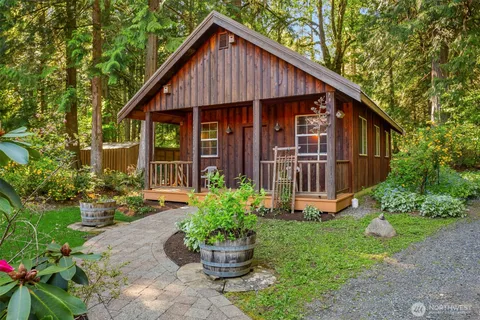a view of a house with wooden walls plants and large trees