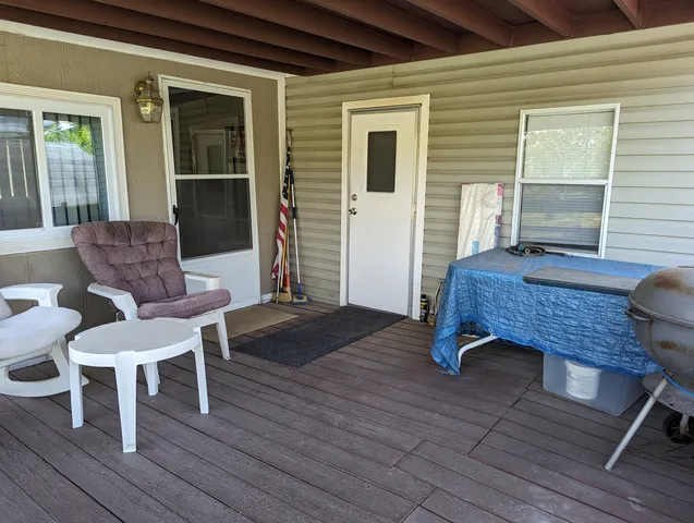 a view of a deck with table and chairs with wooden floor and floor to ceiling window