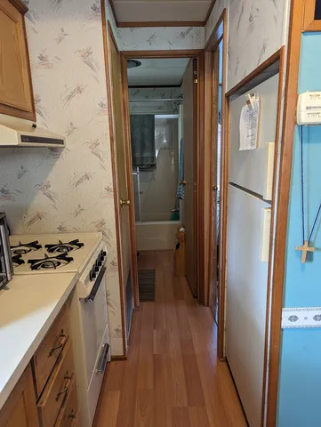 a kitchen with a refrigerator a stove and wooden floor