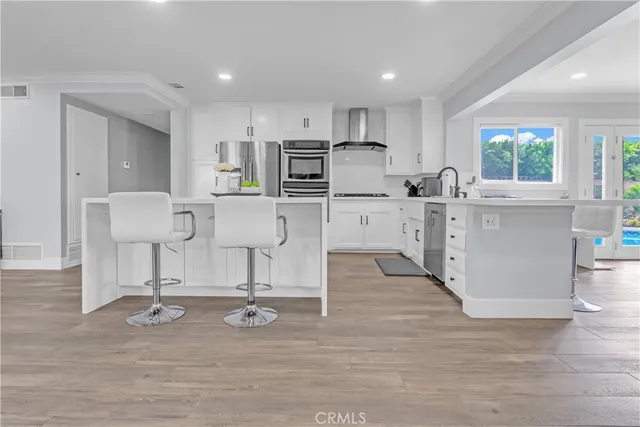 a view of kitchen with center island stainless steel appliances wooden floor and living room view