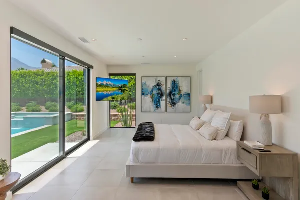 a bedroom with a bed and a large window with the garden view