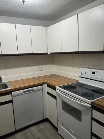 a kitchen with granite countertop white cabinets and white appliances